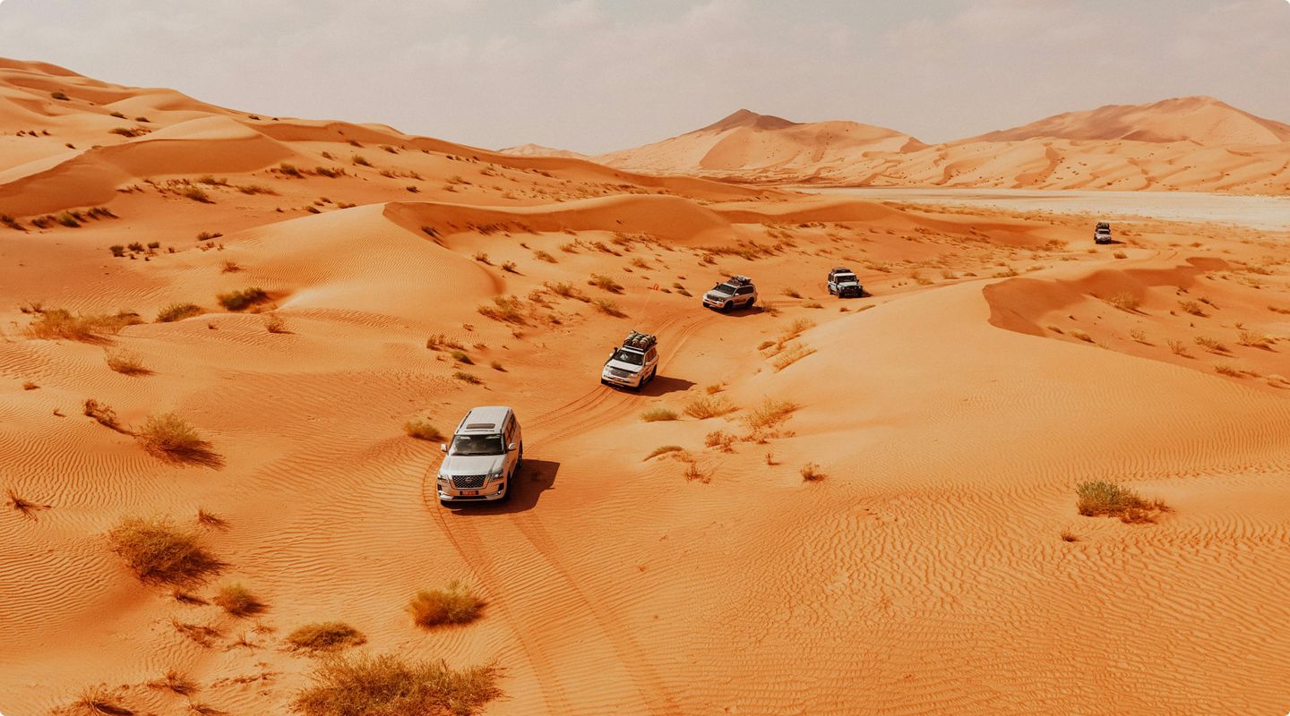 a convoy of five cars driving through the desert