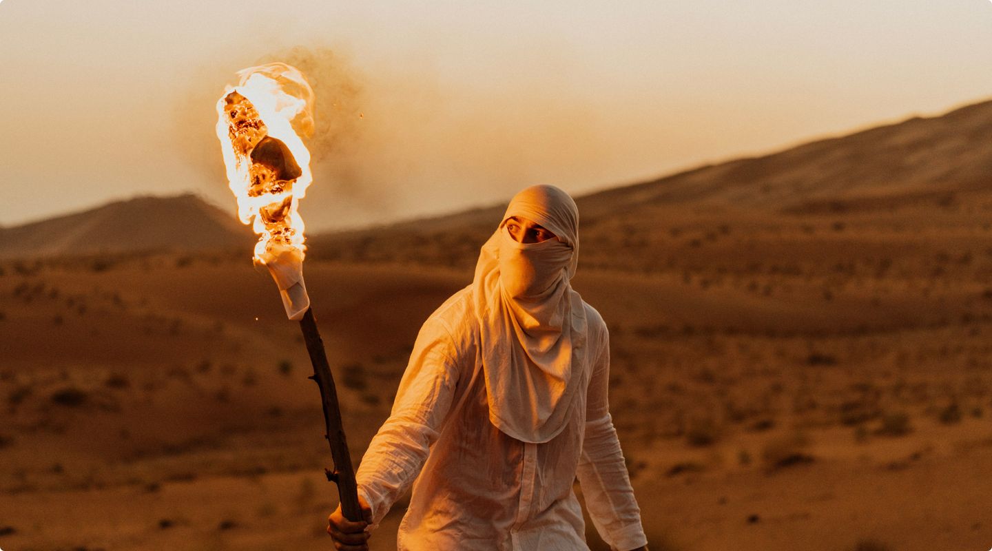 a person holding a fire torch as darkness descends in the desert